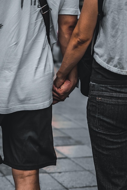 Photo midsection of gay couple holding hands while standing on street