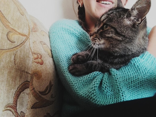 Midsection of girl embracing cat at home