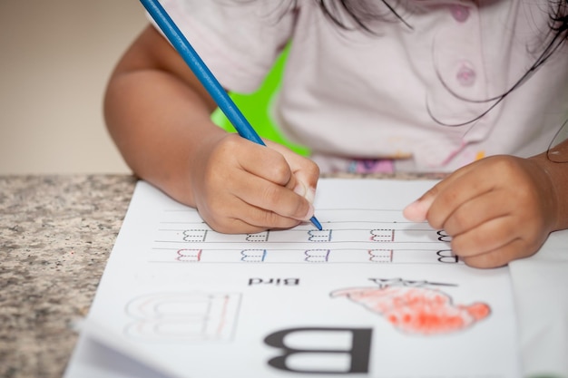 Photo midsection of girl tracing alphabet at home