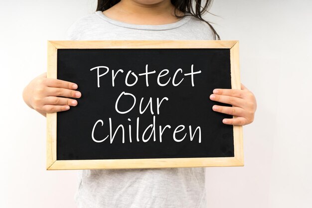 Photo midsection of girl with blackboard standing against white background