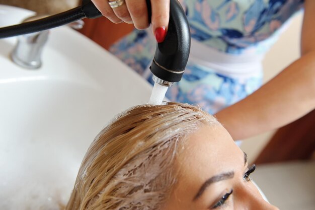 Midsection of hairdresser washing woman hair at salon