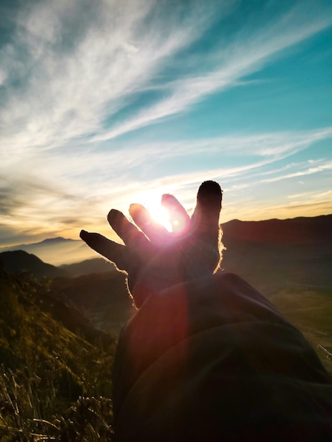 Photo midsection of hands against sky during sunset