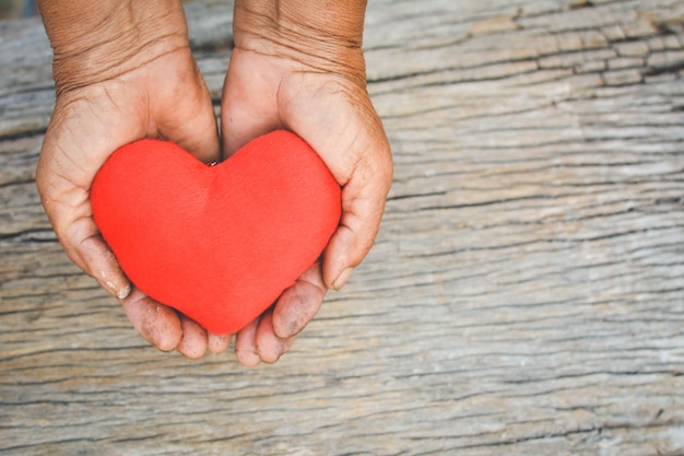 Photo midsection of hands holding heart shape on wood