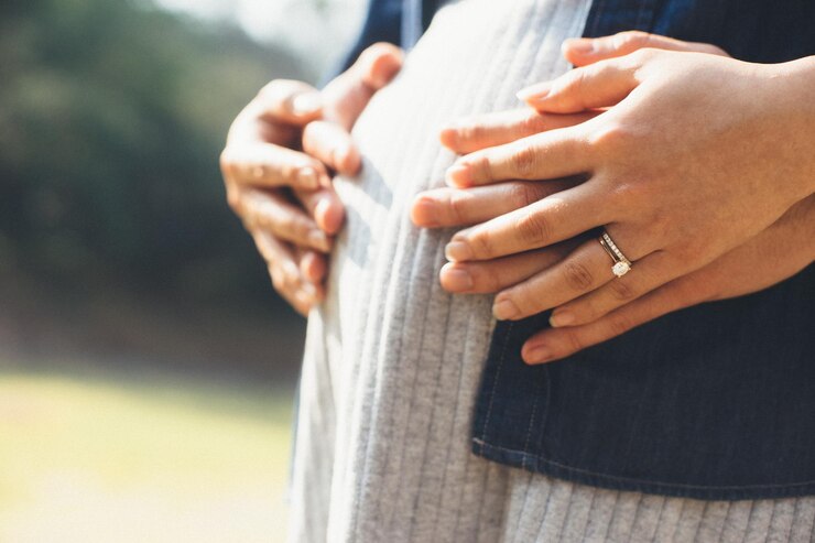 Photo 妊娠中の妻を抱きしめる夫のミッドセクション