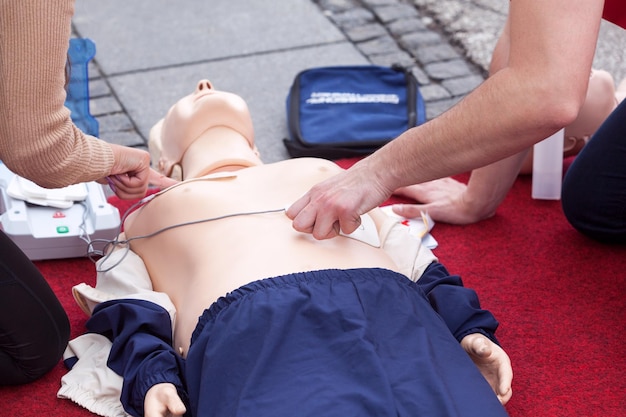 Photo midsection of instructor teaching paramedic while performing cpr on dummy