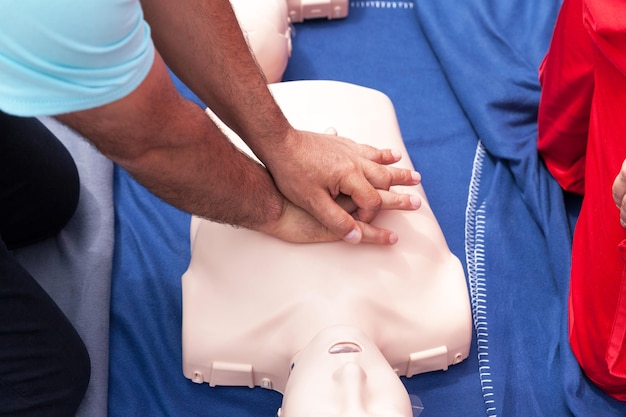 Foto sezione centrale dell'istruttore che insegna al paramedico mentre esegue la rianimazione cardiopulmonare sul manichino