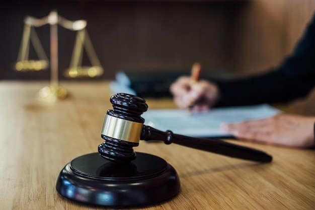 midsection of judge writing with gavel on table