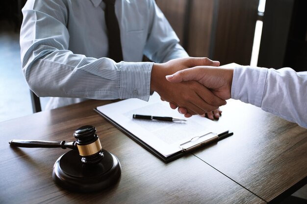 弁護士とクライアントがテーブルに座って握手している中間部分