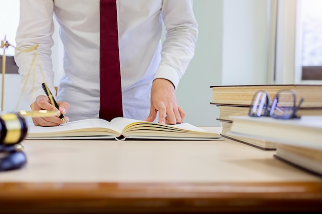 Foto sezione centrale di un avvocato che legge un libro sul tavolo mentre si trova in ufficio