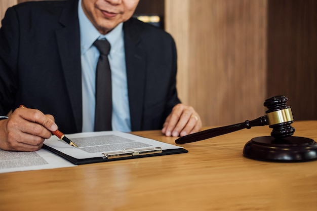 オフィスで木製のテーブルに座って紙を読んでいる弁護士のミッドセクション