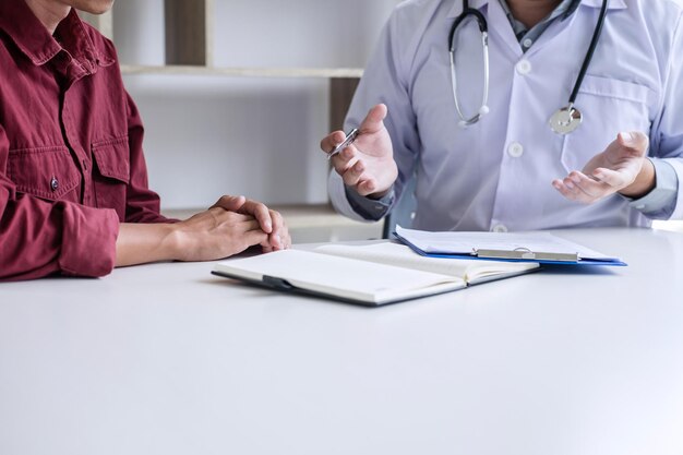 Photo midsection of male doctor discussing with patient in hospital