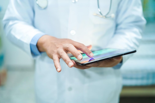 Photo midsection of male doctor using digital tablet while standing in hospital