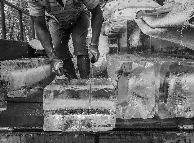Foto sezione centrale di un operaio maschio che taglia il ghiaccio all'aperto