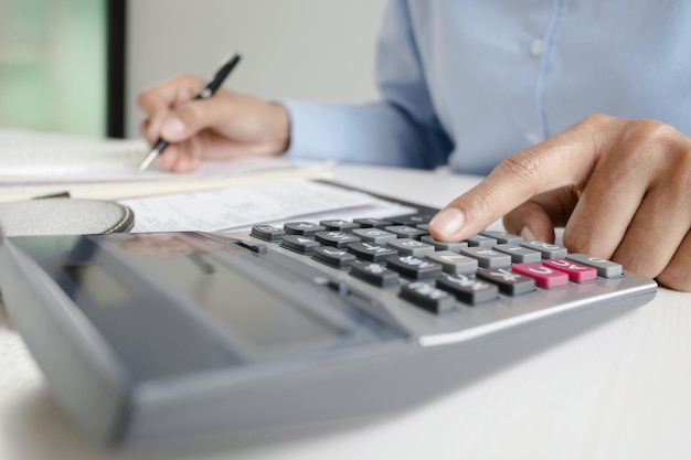 Midsection of man calculating on desk