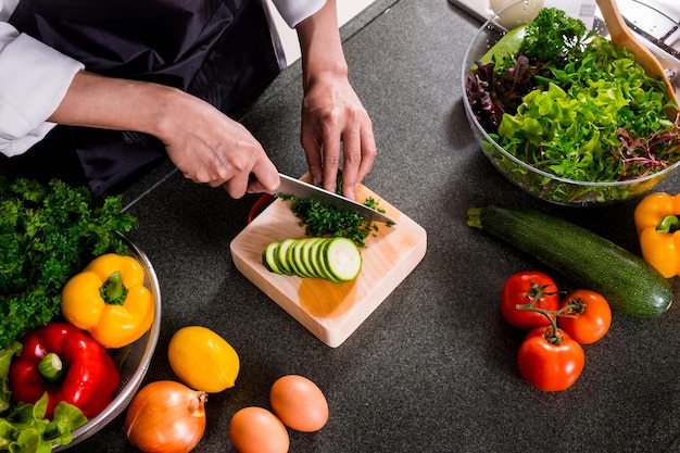 Foto sezione centrale di un uomo che taglia verdure in cucina