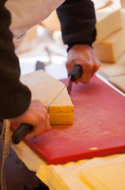 midsection of man cutting cheese on table
