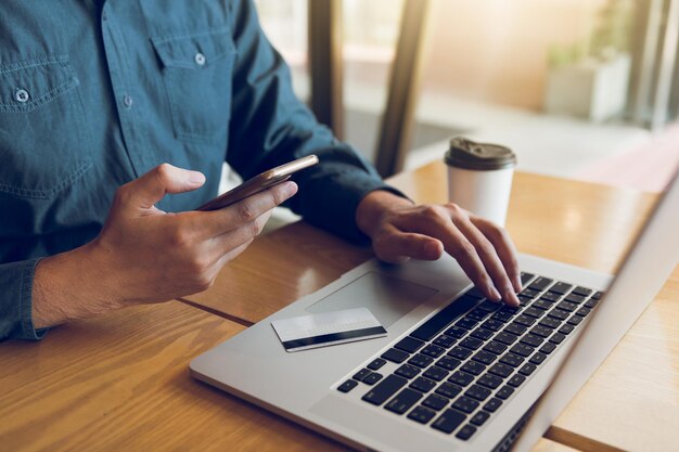 Photo midsection of man doing online shopping through laptop at table