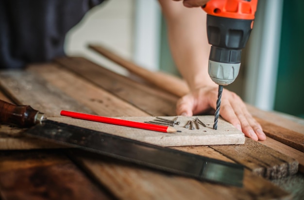 midsection of man drilling in plank at workshop