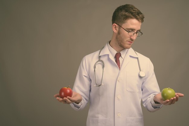 Midsection of man holding apple standing against wall