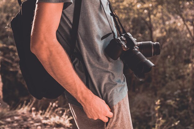 Photo midsection of man holding camera while standing outdoors