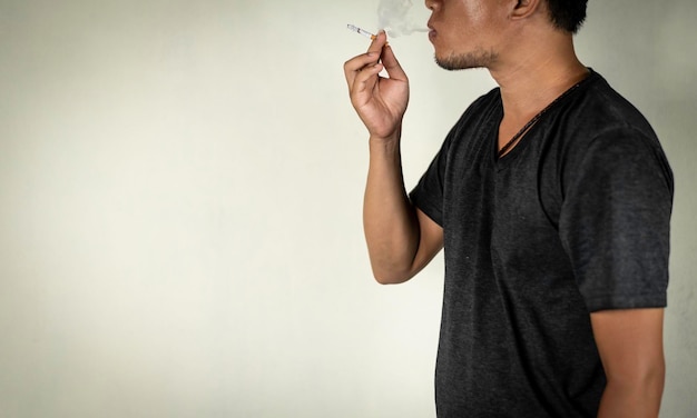 Photo midsection of man holding cigarette against wall