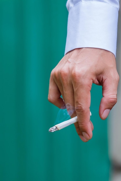 Midsection of man holding cigarette against wall