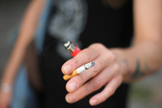 midsection of man holding cigarette