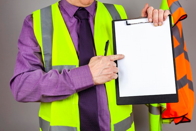 Midsection of man holding clipboard against gray wall