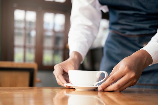 Midsection of man holding coffee cup on table