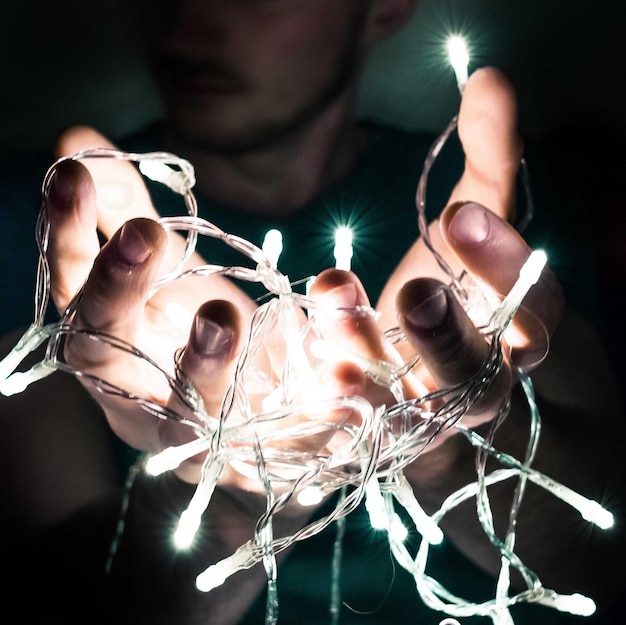 Foto sezione centrale di un uomo che tiene una striscia di luci illuminata