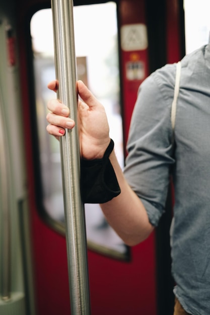 Photo midsection of man holding metallic pole in train