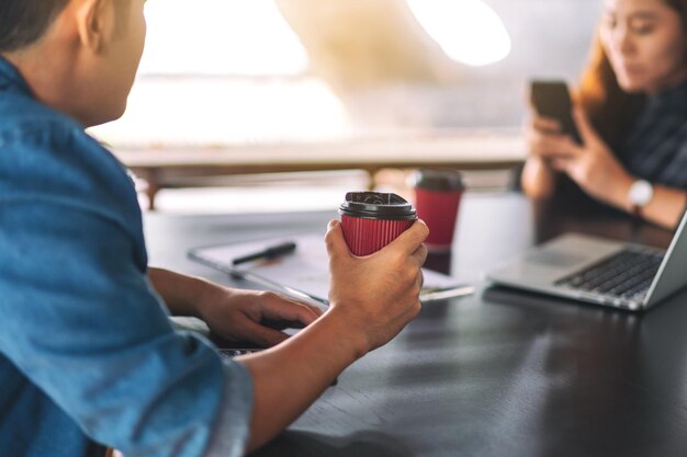 Photo midsection of man holding mobile phone while sitting on table