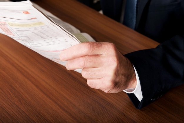 Midsection of man holding newspaper on table