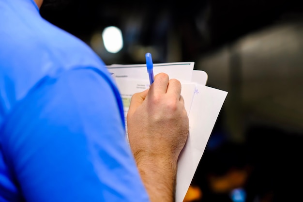 Midsection of man holding paper and pen at night