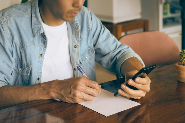 Photo midsection of man holding paper while sitting on table