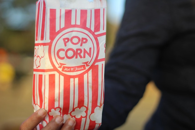 midsection of man holding popcorn bag