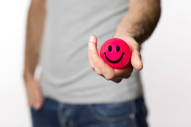 Foto sezione centrale di un uomo che tiene una palla rossa con una faccia sorridente sullo sfondo bianco