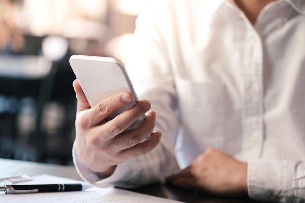 Midsection of man holding smart phone on table