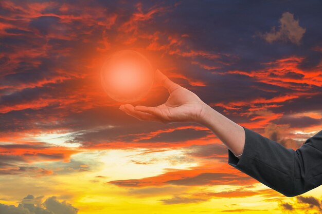 Midsection of man holding sun during sunset