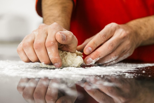 midsection of man kneading dough at kitchen