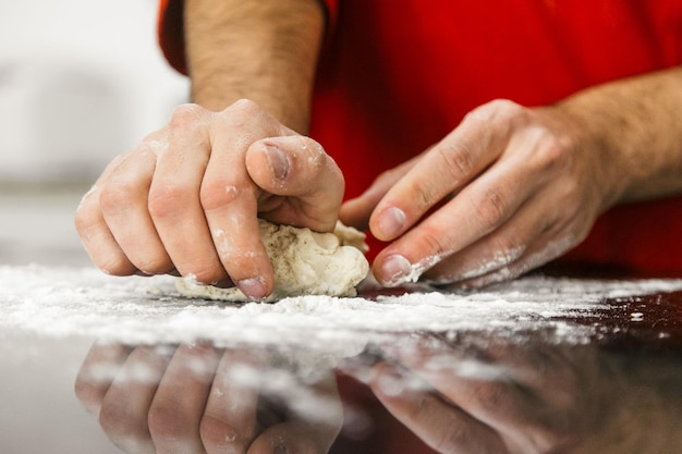 Foto sezione centrale di un uomo che impasta la pasta in cucina