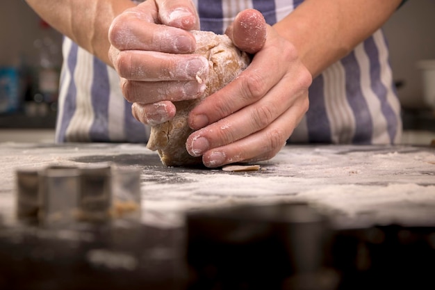 Midsection of man kneading dough on table in kitchen