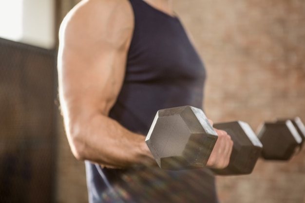 Photo midsection of man lifting dumbbells