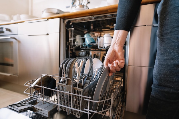 Photo midsection of man loading dishwasher machine in kitchen at home