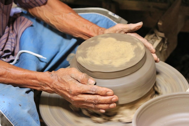 midsection of man molding shape on pottery wheel