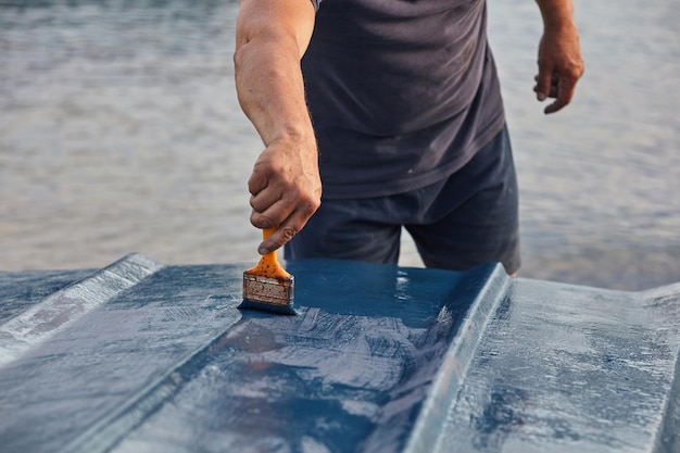 Midsection of man painting nautical vessel