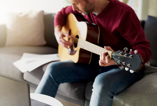 Foto sezione centrale di un uomo che suona la chitarra a casa