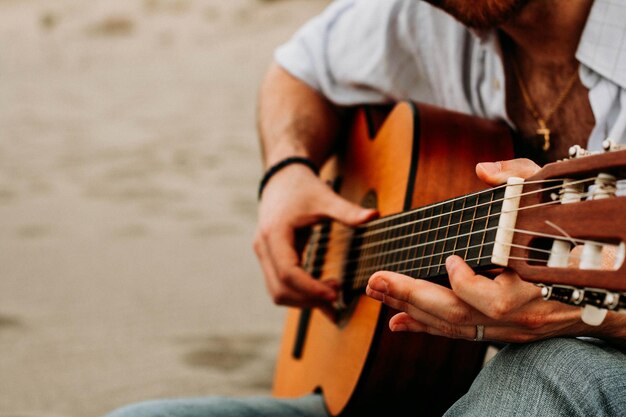 Midsection of man playing guitar while sitting outdoors