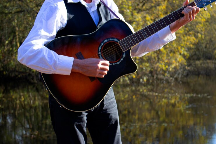 Photo midsection of man playing guitar while standing against lake