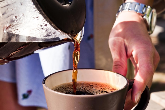 カップにコーヒーを注ぐ男の真ん中